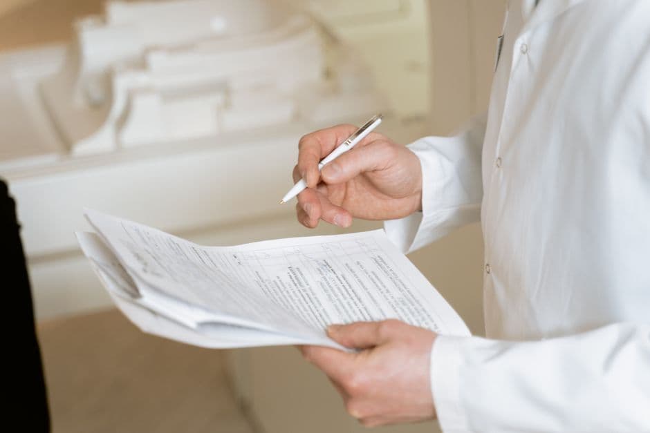 A doctor holds and reviews medical documents, demonstrating careful examination and professionalism.